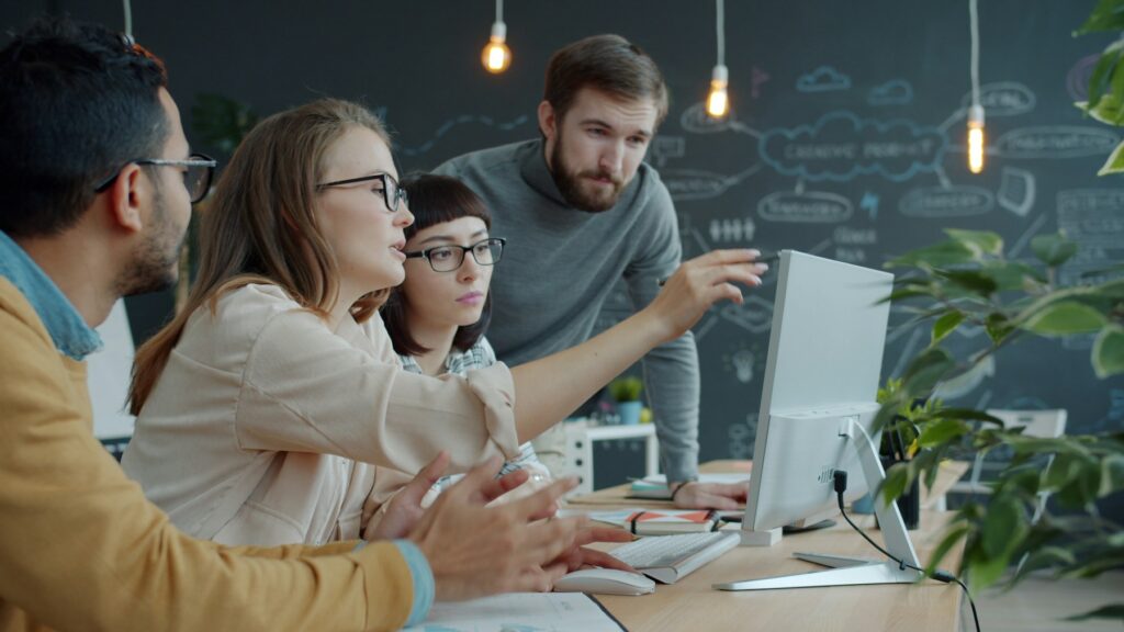 Team collaborating around a computer in an office.